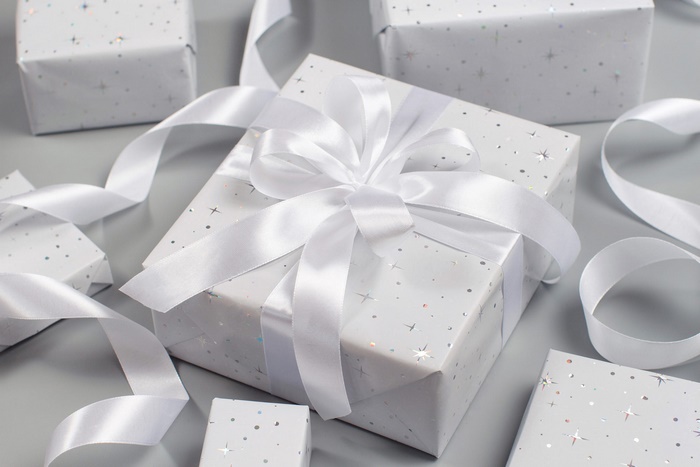Gifts wrapped in white paper with silver stars and white ribbon