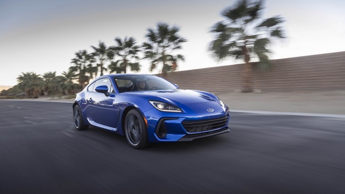 Blue Subaru BRZ driving on a road with palm trees