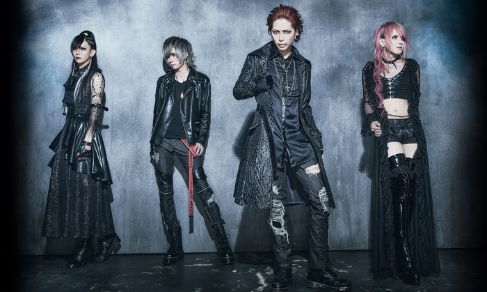 Four individuals in gothic attire posing against a textured wall