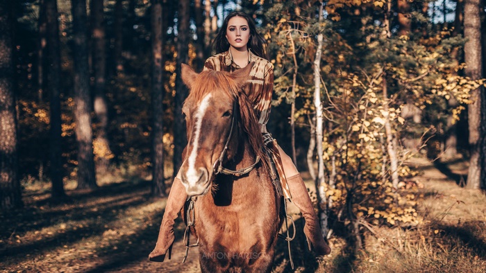 Woman riding a brown horse in a forest