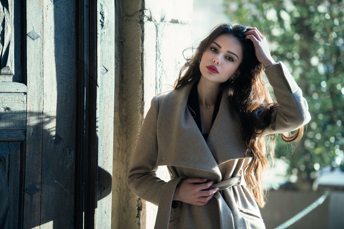 Woman in elegant coat standing by a doorway