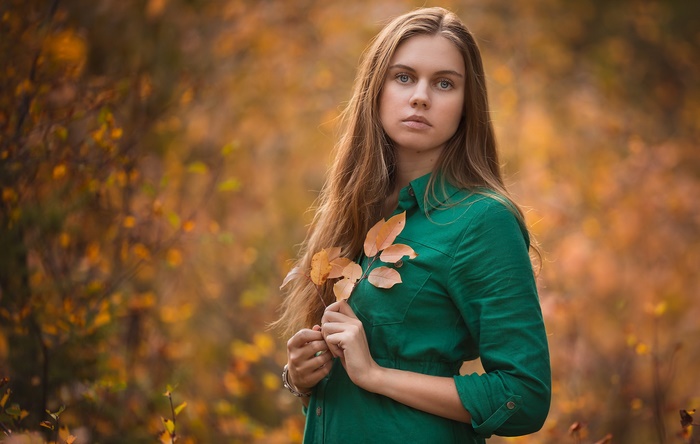 Woman in green shirt holding autumn leaves