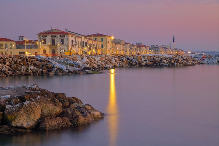 Marina di Pisa waterfront at dusk with rocky breakwater
