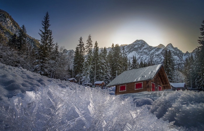 Winter cabin in snowy mountains with ice formations