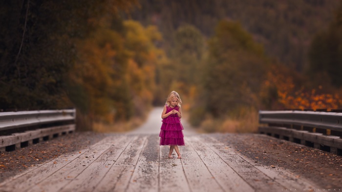 Girl in pink dress on a wooden bridge in autumn