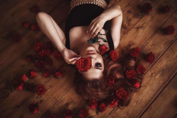 Woman lying on floor with red roses