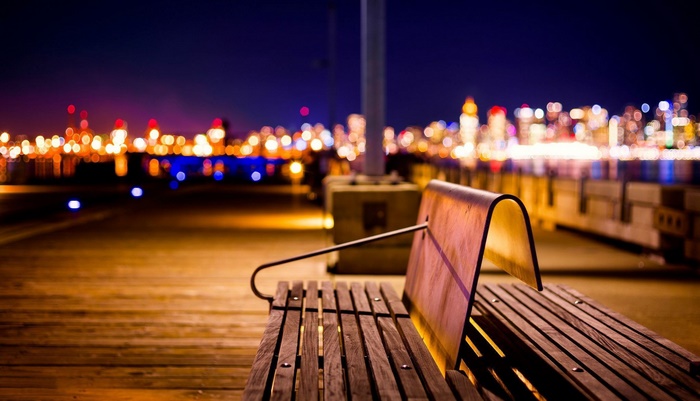 Wooden bench at night with city lights bokeh