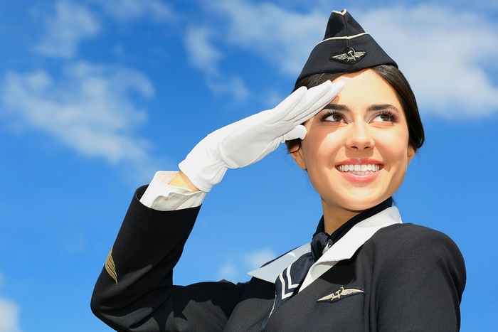 Flight attendant saluting against a blue sky