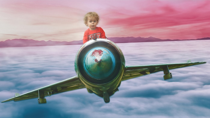 Child riding an airplane over clouds
