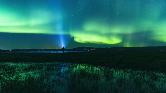 Man with flashlight watching Aurora Borealis in Iceland