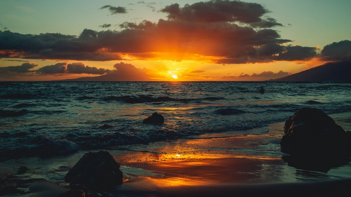 Sunset over the ocean with a beach and mountains