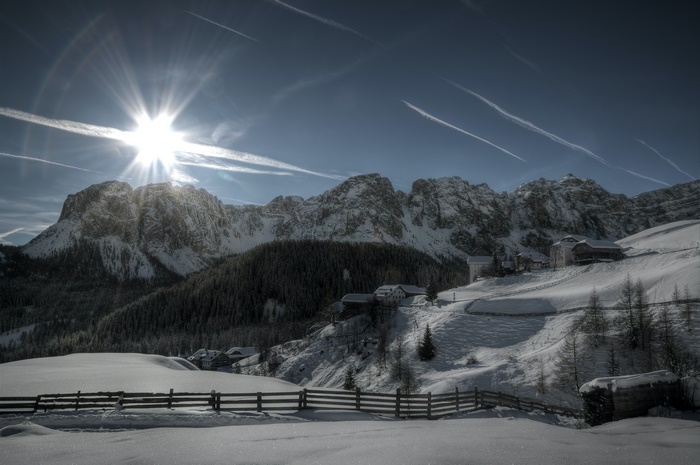 Winter mountain landscape with sun and houses