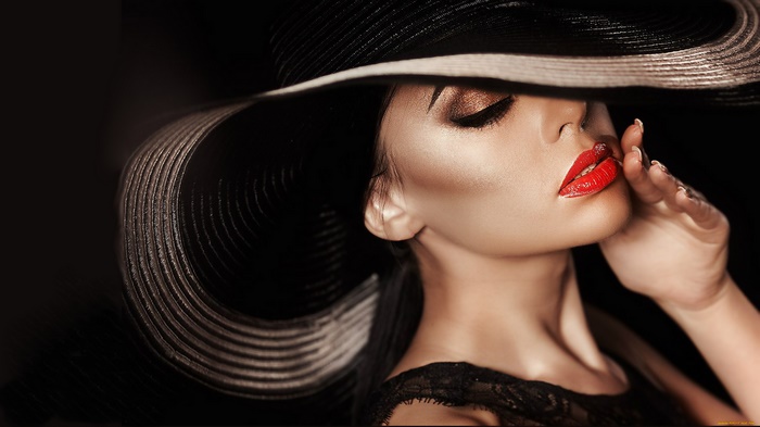 Woman wearing a large black hat and red lipstick