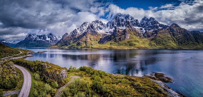 Road along a fjord with snow-capped mountains in Lofoten Islands, Norway