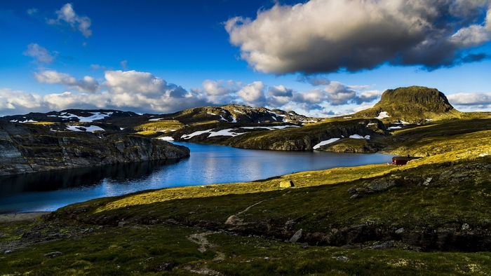 Lake and mountains in Norway with a red cabin