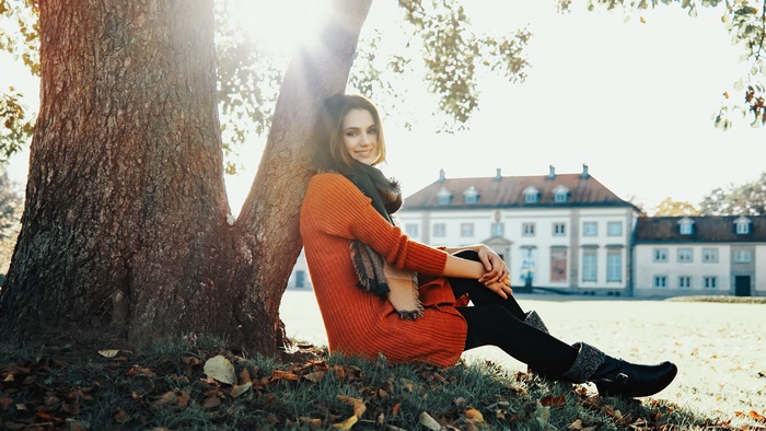Smiling Model Sitting by Tree in Sunlight