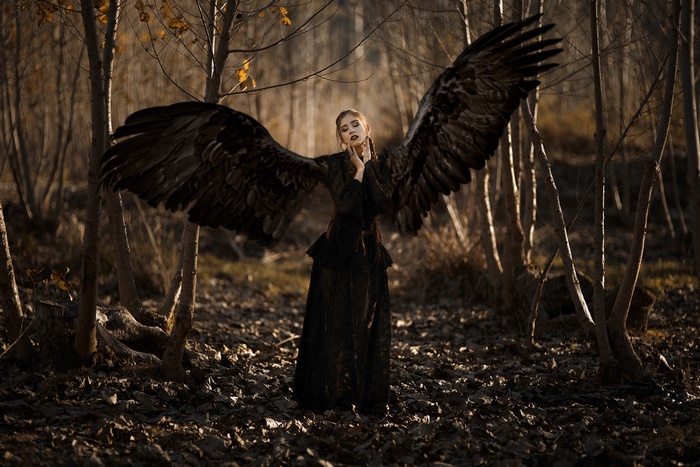 Woman with black wings in a dark forest