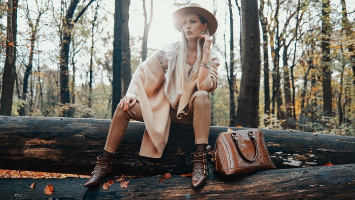 Woman in hat and coat sitting on a log