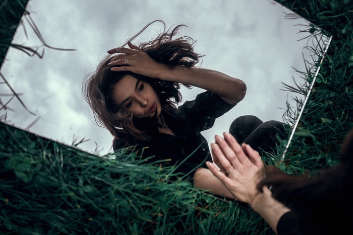 Woman reflected in a mirror on grass