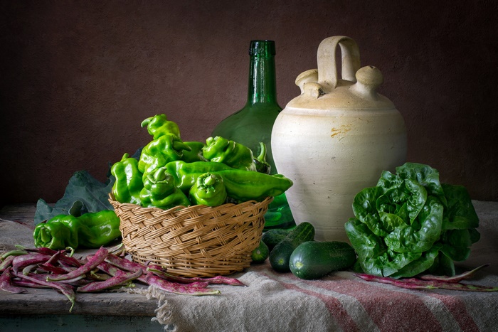 Still life with peppers, lettuce, cucumbers, beans, jug, and bottle