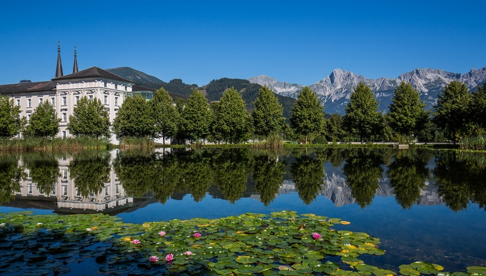 Admont Abbey reflected in a pond with water lilies and mountains