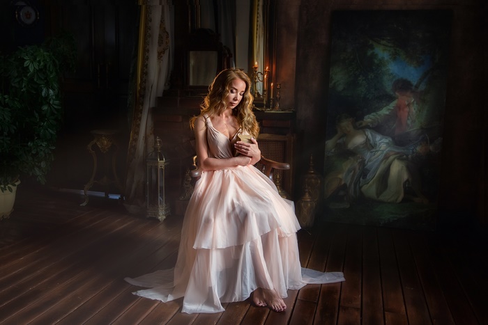 Woman in a flowing dress holding a book in a dimly lit room