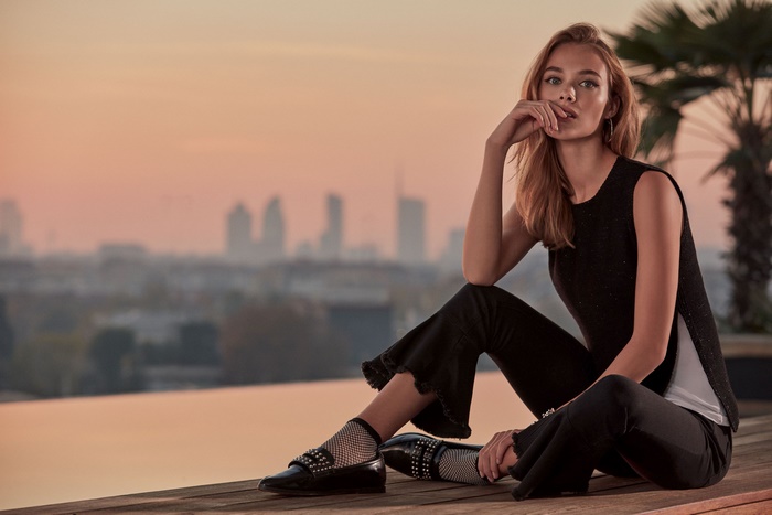 Woman sitting on a wooden deck at sunset