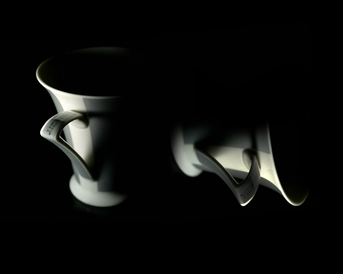 Two white cups with handles on black background