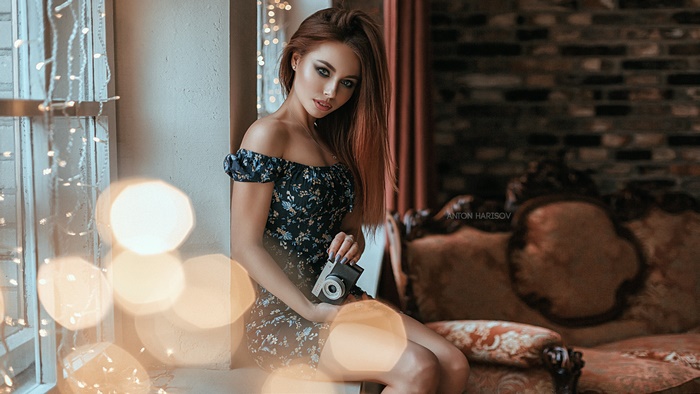 Woman with camera in a room with bokeh lights