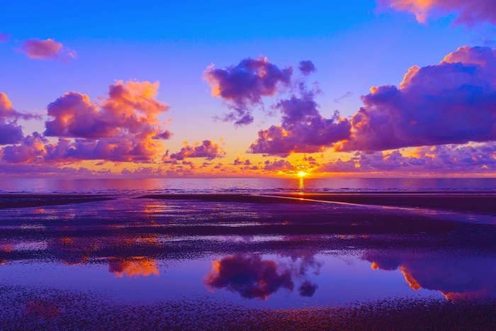 Sunset over the sea with colorful clouds and reflections