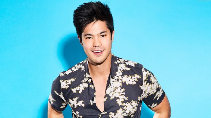 Ross Butler smiling against a blue background