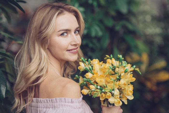 Blonde Woman with Blue Eyes Holding Yellow Flowers