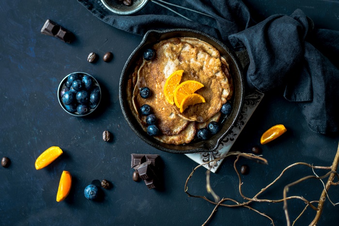 Pancakes with blueberries and orange slices in a cast iron skillet