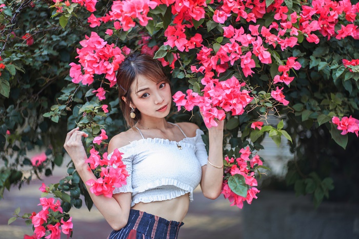 Asian woman posing near pink bougainvillea flowers