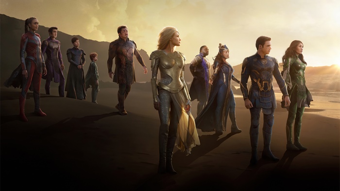 The Eternals standing on a beach at sunset