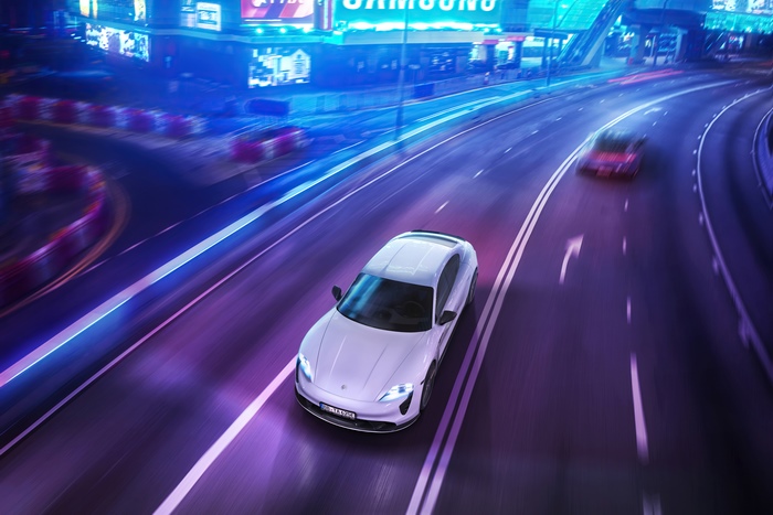 Porsche Taycan Turbo S driving on a neon-lit street