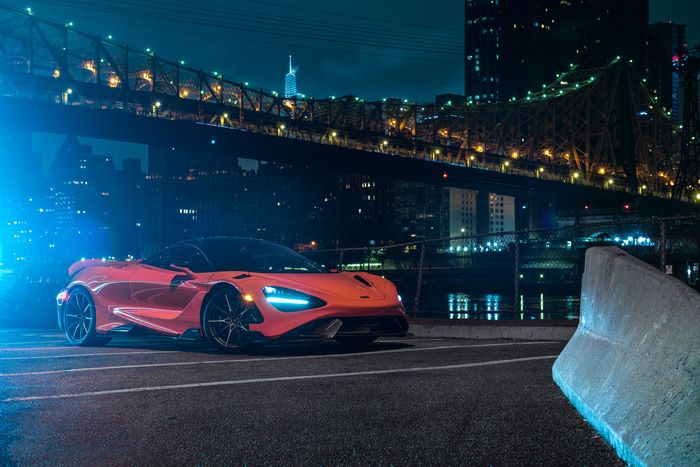 Orange McLaren 765LT parked near a bridge at night
