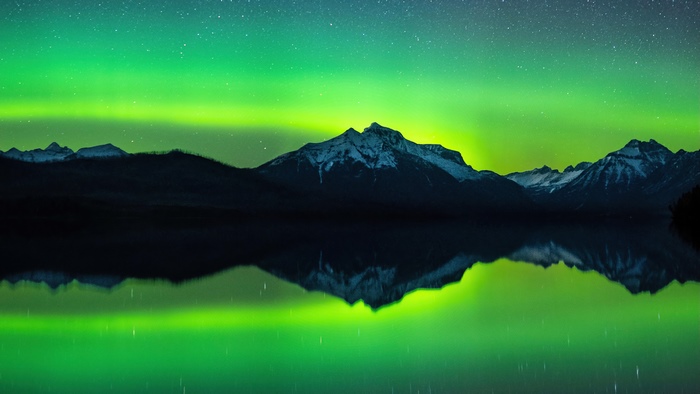 Aurora Borealis over snow-capped mountains reflected in a lake