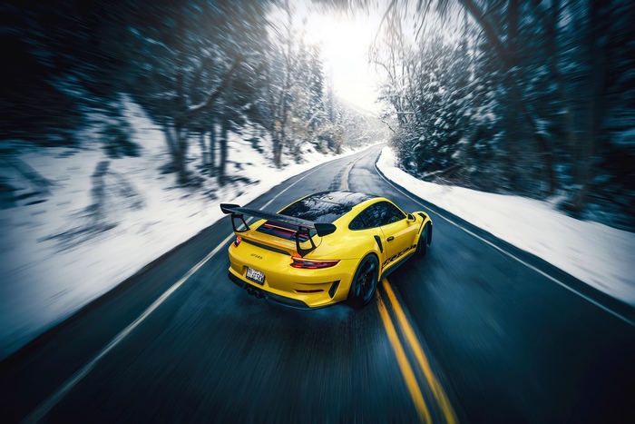Yellow Porsche GT3 driving on a snowy road