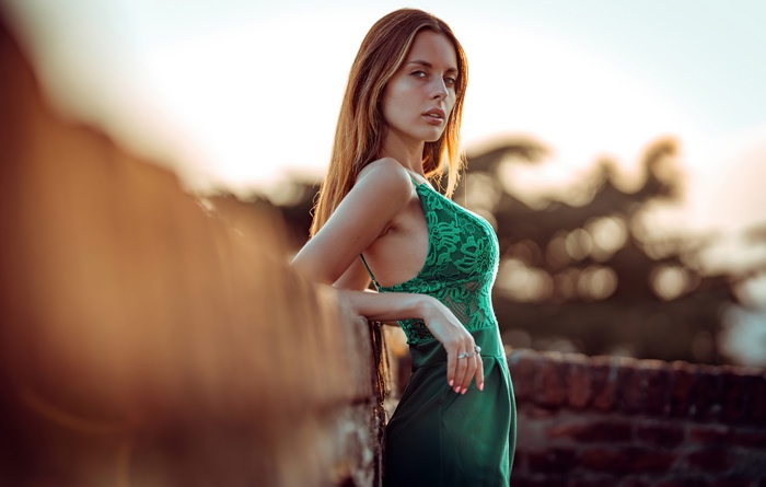 Woman in green lace dress leaning on wall