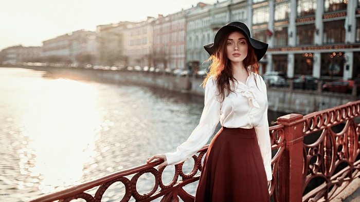 Woman in hat and white blouse by river