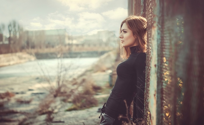 Woman in black turtleneck leaning against fence
