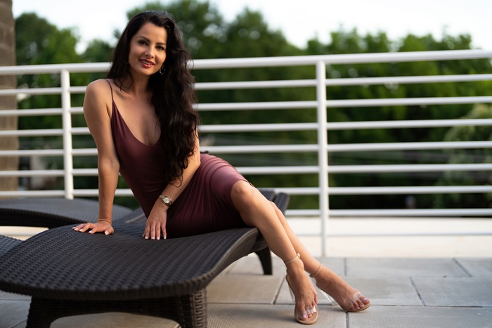 Brunette woman in elegant dress posing on lounge chair