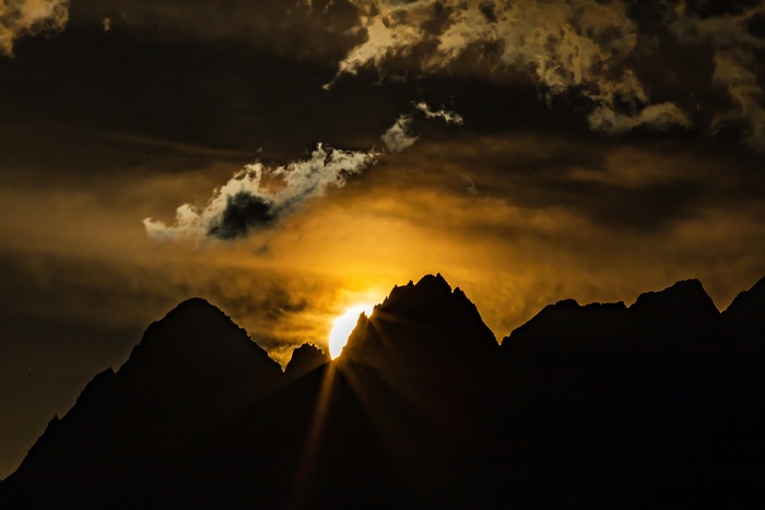 Sunset over silhouetted mountains with dramatic clouds