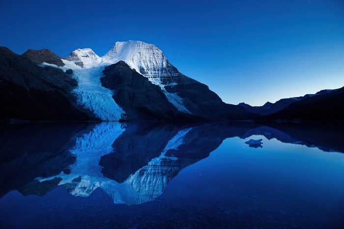 Mountain glacier reflected in a lake at dusk