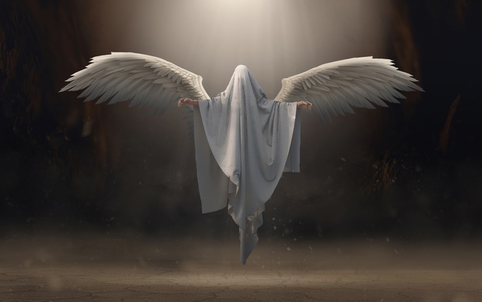 Angel with white wings in a dark cave