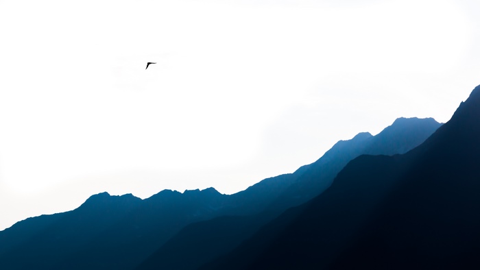 Silhouette of a hang glider over mountains