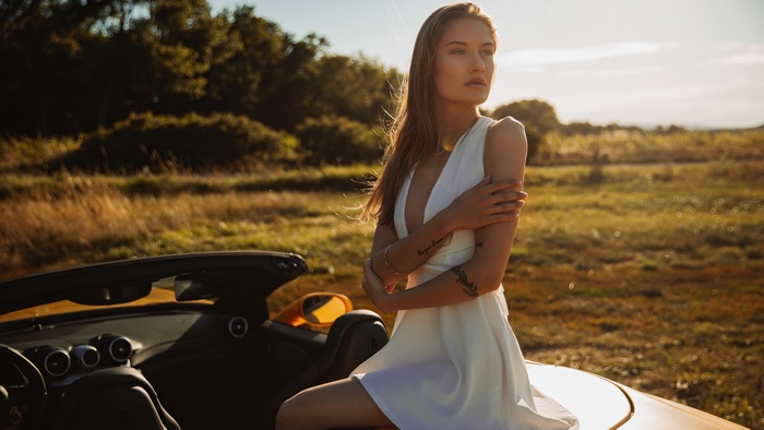 Model in white dress by a convertible car