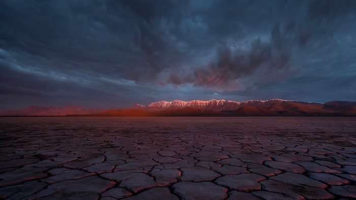 Cracked desert landscape with mountains at sunset 4K