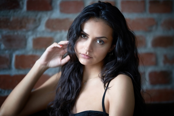Model with dark wavy hair against brick wall